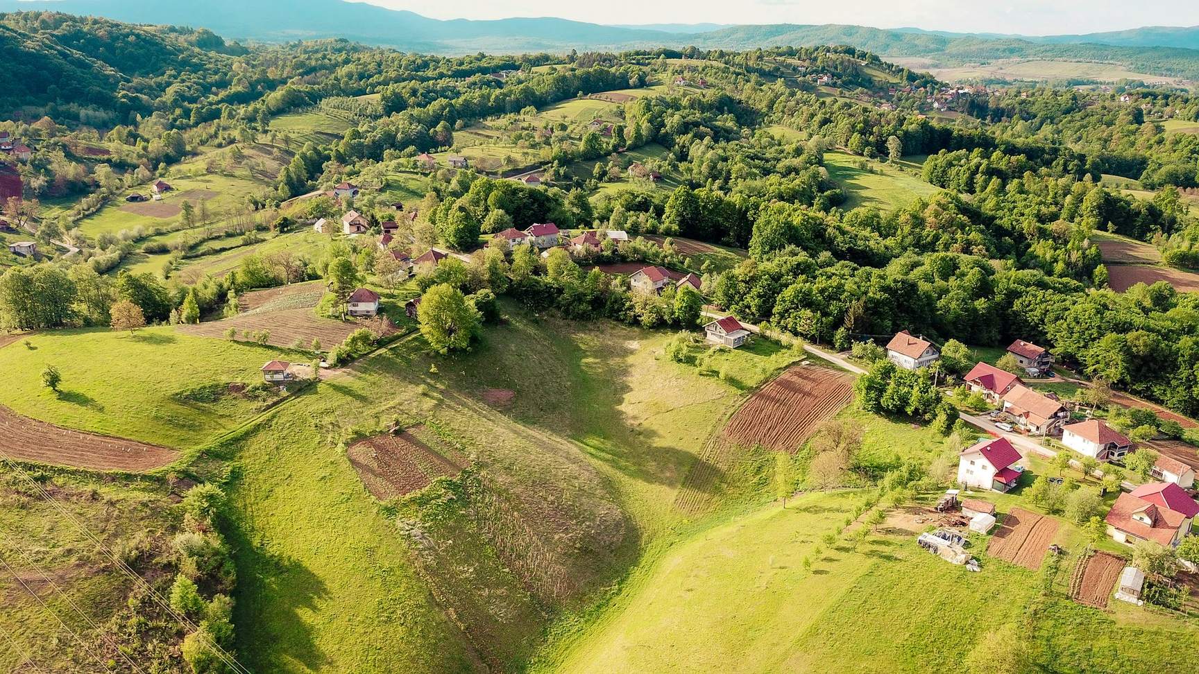Vista aérea de colinas verdes com pequenas casas espalhadas pelo campo