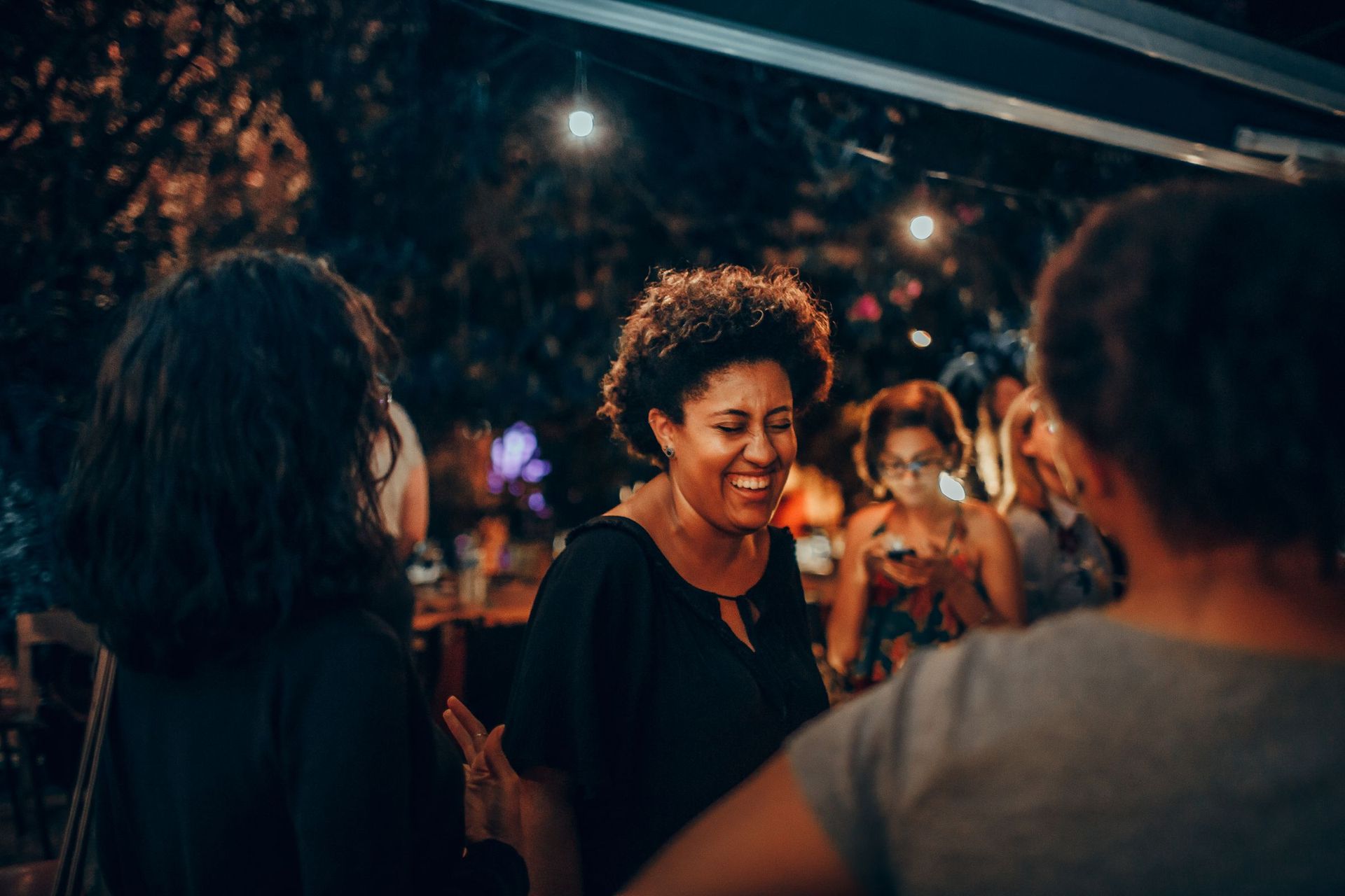 Mulheres sorrindo e conversando em uma confraternização ao ar livre à noite