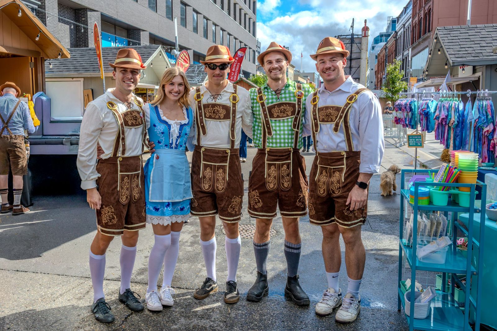 Grupo de adultos vestindo trajes típicos alemães, como lederhosen e dirndl, em uma rua