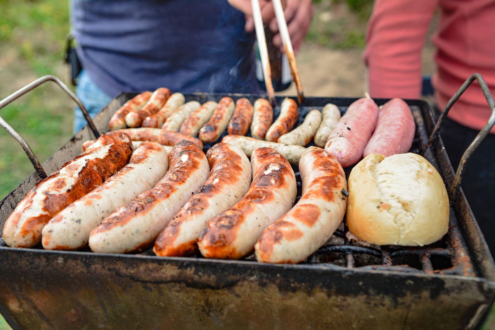 Linguiças e pão assando em uma grelha ao ar livre