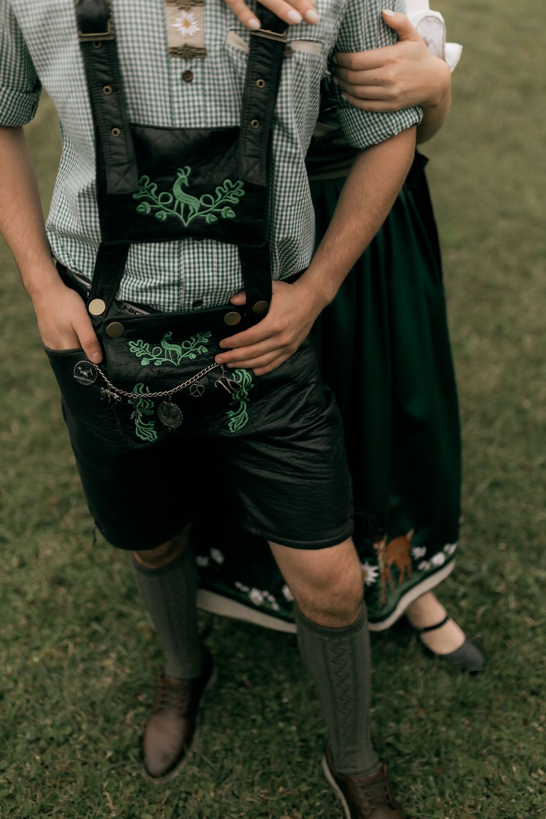 Detalhe de trajes típicos: calça de couro bordada (lederhosen) e vestido tradicional sobre gramado