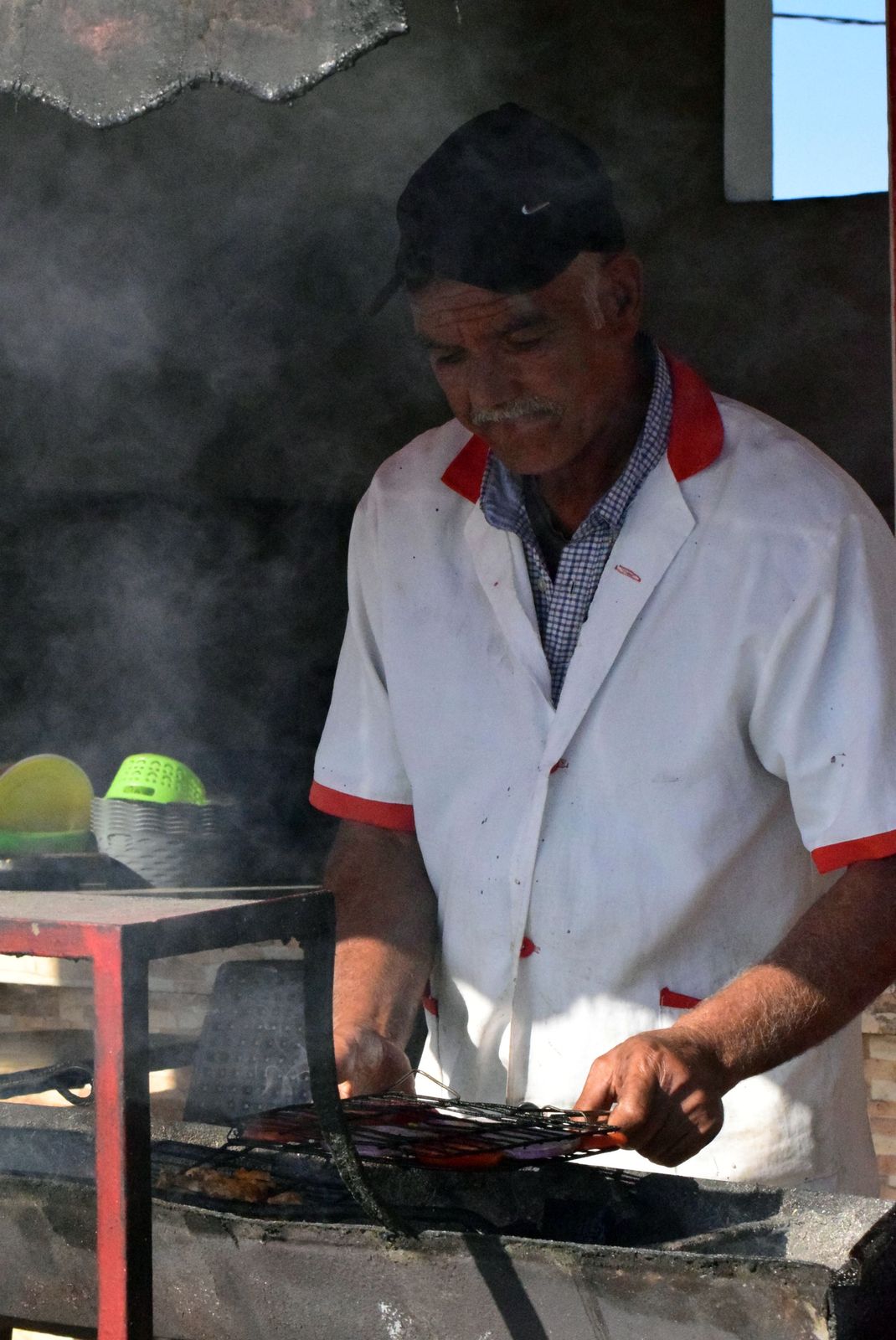 Cozinheiro preparando carne em uma grelha com fumaça